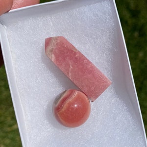 May include: A pink and white crystal sphere and a pink and white crystal point in a white box with white padding.