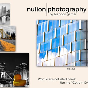May include: A black and white photograph of a city skyline with a bridge in the foreground. The bridge is yellow and has a road going over it. The city skyline is in the background and is made up of tall buildings. The photograph is in a standard aspect ratio and is available in various sizes, including 8x10, 11x14, 16x20, and 20x30 inches.