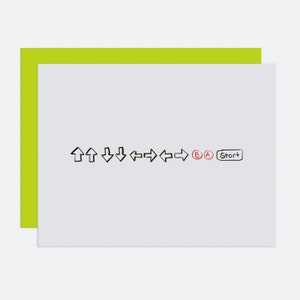 May include: A white card with black and red arrows, letters, and the word "Start" written on it. The card is on top of a bright green card.