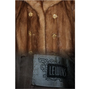 Peut inclure: Un manteau en fourrure marron avec des boutons dor&eacute;s et une &eacute;tiquette noire qui dit "Lewins".