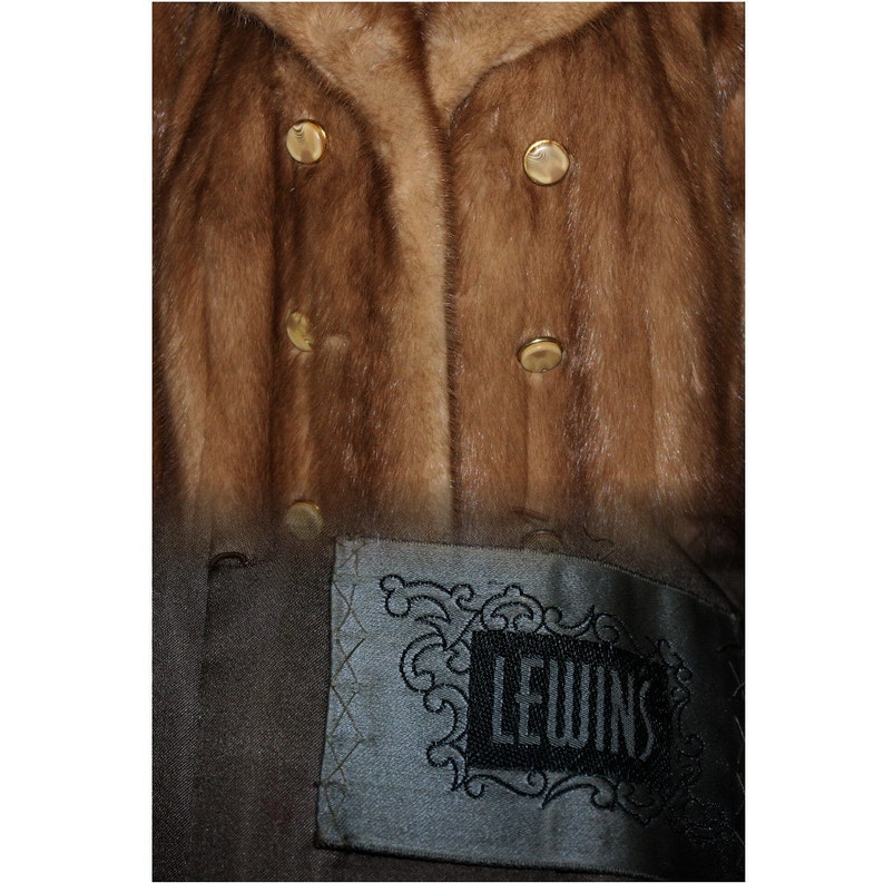 Peut inclure: Un manteau en fourrure marron avec des boutons dor&eacute;s et une &eacute;tiquette noire qui dit "Lewins".