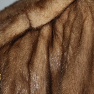 Peut inclure: Un manteau en fourrure marron avec une fermeture &agrave; bouton. La fourrure est douce et luxueuse.