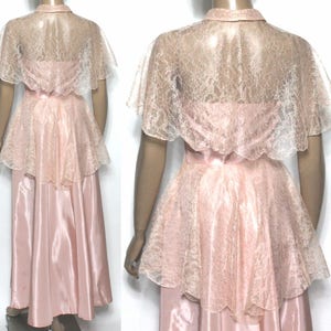 May include: A pink satin and lace dress with a lace cape. The dress has a fitted bodice and a full skirt. The cape is sheer and has a scalloped edge.