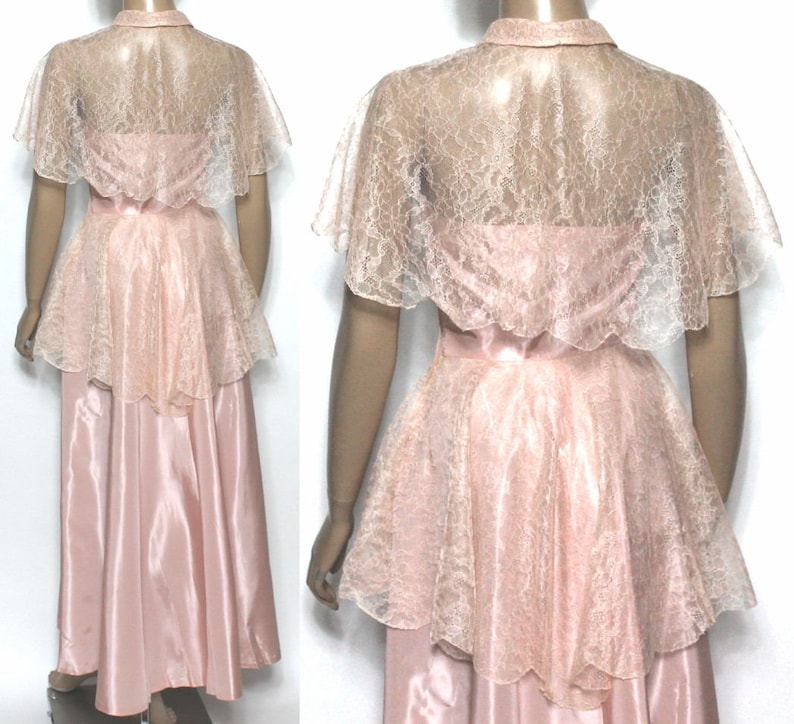 May include: A pink satin and lace dress with a lace cape. The dress has a fitted bodice and a full skirt. The cape is sheer and has a scalloped edge.