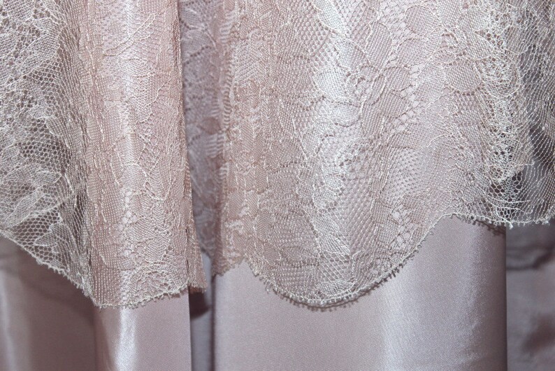 May include: Close-up of a delicate, off-white lace fabric with a floral pattern. The lace is soft and flowing, with a subtle sheen.