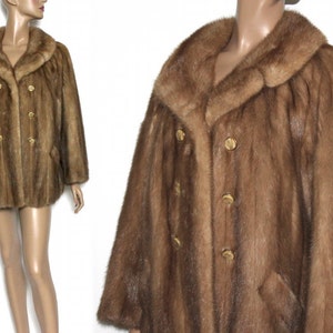 Peut inclure: Un manteau en fourrure marron &agrave; double boutonnage et un grand col. Le manteau a des boutons dor&eacute;s.