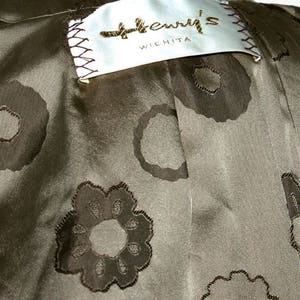 K&ouml;nnte beinhalten: Ein brauner Stoff mit einem Etikett, auf dem "Henry's Wichita" steht, und einem Muster aus gestickten Blumen.