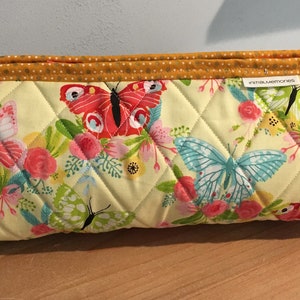 May include: Quilted fabric bag with a yellow background and a butterfly and floral pattern. The bag has a yellow handle with a polka dot design and red accents. The text "inmalumoments" is visible on the side.