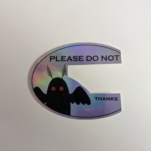 Puede incluir: Una pegatina hologr&aacute;fica con una criatura negra con ojos rojos y el texto "PLEASE DO NOT THANKS" en negro.