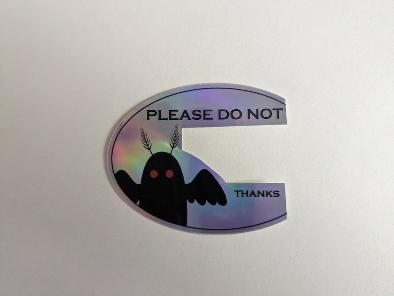 Puede incluir: Una pegatina hologr&aacute;fica con una criatura negra con ojos rojos y el texto "PLEASE DO NOT THANKS" en negro.