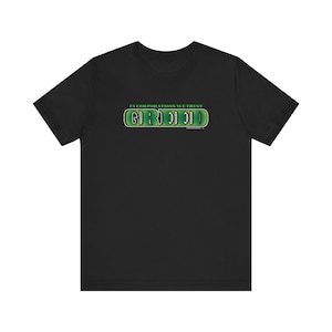 May include: Black t-shirt with a green and white graphic that says "In Corporations We Trust - Greed".