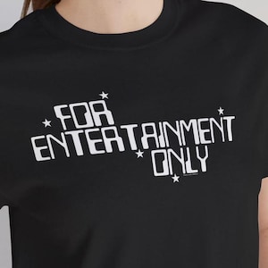 Könnte beinhalten: Schwarzes T-Shirt mit weißem Text, der "FOR ENTERTAINMENT ONLY" lautet, mit Sternen um den Text herum.