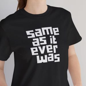 May include: Black t-shirt featuring the white phrase "same as it ever was" in a bold, blocky font. The t-shirt has a crew neck design, suitable for everyday wear.