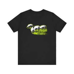 May include: Black t-shirt with a graphic of four white sheep walking in a line on a green field. The text "SELLOUT" is printed below the sheep.