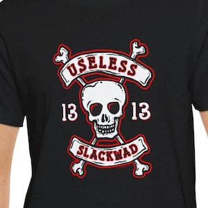 May include: Black t-shirt with a white skull and crossbones graphic. The graphic includes the text "Useless 13 Slackwad 13".