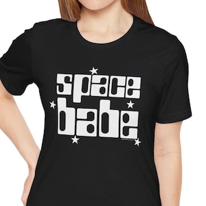 Könnte beinhalten: Schwarzes T-Shirt mit weißem Text, der "space babe" lautet, mit Sternen um den Text herum.