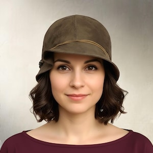 May include: An olive green cloche hat with a rounded crown, a short asymmetrical brim, and a thin cord detail wrapped around the base. The text "Elsewchen SEWING PATTERN" and "INSTANT PDF DOWNLOAD" is visible on the sides of the image.