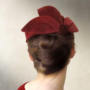 May include: A deep red velvet hat featuring a structured, multi-layered petal design and a central circular accent. The text "Elsechen SEWING PATTERN" and "INSTANT PDF DOWNLOAD" is visible on the left and right sides of the image.