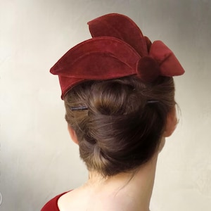 May include: A deep red velvet hat featuring a structured, multi-layered petal design on the top and a circular accent piece on the side. The text "Elsewchen SEWING PATTERN" and "INSTANT PDF DOWNLOAD" is visible on the left and right sides.