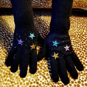 May include: A pair of black long fingered gloves with colorful star-shaped embellishments.