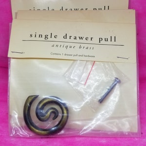May include: A single drawer pull in antique brass finish. The pull is a spiral design and comes with a screw. The packaging says "single drawer pull antique brass" and "Contains 1 drawer pull and hardware".