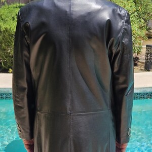 Pu&ograve; includere: Un blazer in pelle nera caratterizzato da un classico colletto a revers, maniche lunghe con tre bottoni su ogni polsino e una cucitura orizzontale sulla parte bassa della schiena. La giacca presenta una finitura liscia e una linea strutturata.