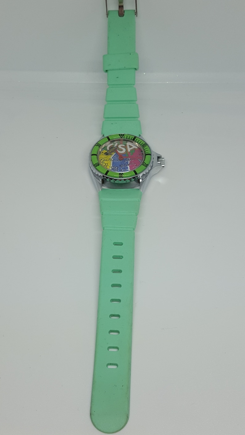May include: A green wristwatch with a colorful face and a green rubber band.