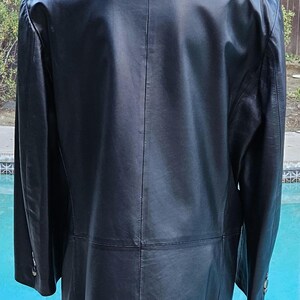 Pu&ograve; includere: Un blazer in pelle nera con colletto classico, maniche lunghe con polsini abbottonati e una cucitura verticale che corre lungo il centro della schiena. La giacca ha una finitura liscia e un orlo dritto, offrendo un aspetto strutturato.