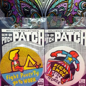 May include: Two circular sew-on patches in clear plastic packaging. The left patch is yellow with a figure and the text "Fight Poverty go to WORK". The right patch is white with a figure and the text "FIGHT SMOG RIDE A HORSE". Both feature the Impko logo.