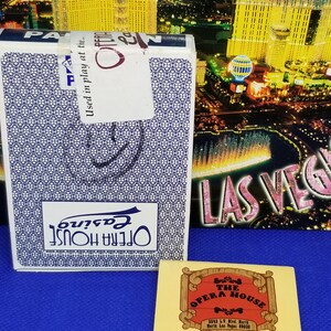 May include: A vintage matchbook for The Opera House Gambling Hall and Saloon in North Las Vegas, Nevada. The matchbook is yellow with a red and white illustration of a wooden sign with the text "The Opera House" and the address "2542 LV. Blvd. North, North Las Vegas 89030". The matchbook also has the text "Gambling Hall and Saloon" and "Universal Match Corp. Las Vegas".