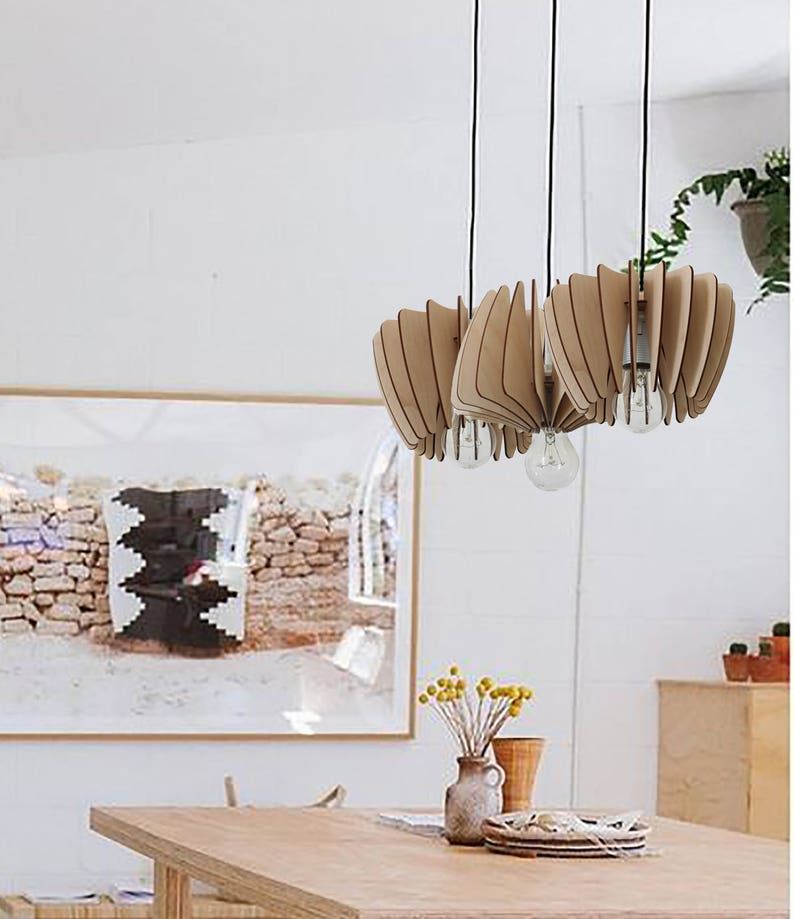 May include: A wooden pendant light fixture with a unique, geometric design. The light fixture is made of multiple thin pieces of wood that are arranged in a fan-like pattern. The light fixture is hanging from the ceiling and is illuminating a dining room table.