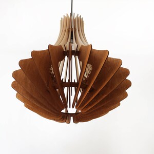 May include: A wooden pendant light fixture with a layered, fan-like design. The light fixture is made of light and dark brown wood, with a bulb visible inside. The fixture hangs from a black cord against a white background.