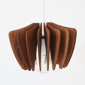 May include: A wooden pendant light fixture with a brown finish. The light fixture is made of multiple thin wooden slats that are arranged in a circular pattern. The light fixture is hanging from a white cord.