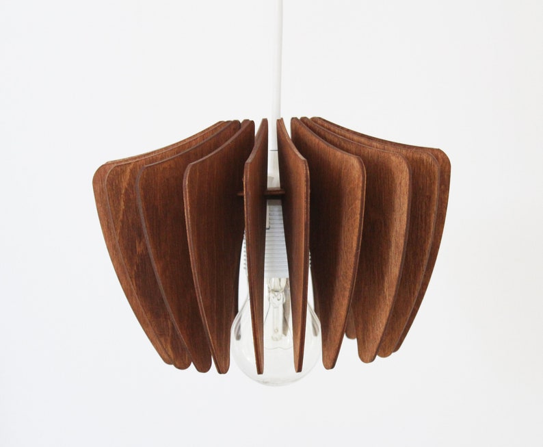 May include: A wooden pendant light fixture with a brown finish. The light fixture is made of multiple thin wooden slats that are arranged in a circular pattern. The light fixture is hanging from a white cord.