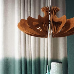 May include: A wooden ceiling light fixture with a unique, geometric design. The light fixture is made of multiple layers of wood that are arranged in a circular pattern. The light fixture is hanging from the ceiling and is illuminated by a light bulb.