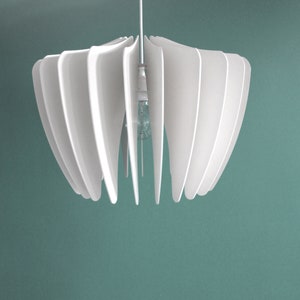 May include: White pendant light fixture with a modern design. The light fixture has a series of overlapping, curved panels that create a flower-like shape.