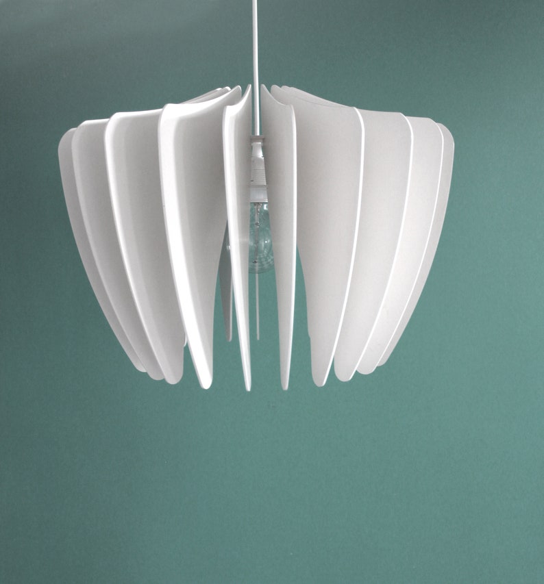 May include: White pendant light fixture with a modern design. The light fixture has a series of overlapping, curved panels that create a flower-like shape.