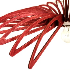 May include: A red wooden ceiling light fixture with a single light bulb. The fixture is made of thin, curved pieces of wood that are arranged in a radial pattern.