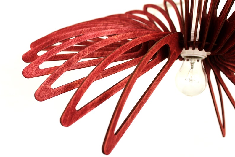 May include: A red wooden ceiling light fixture with a single light bulb. The fixture is made of thin, curved pieces of wood that are arranged in a radial pattern.