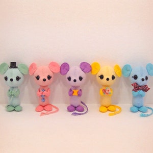 May include: Five felt mouse plushies in a row. The mice are light blue, pink, purple, yellow, and blue. Each mouse has a different design on its chest.