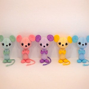 May include: Five felt mouse toys lined up. The mice are light blue, pink, purple, yellow, and blue. Each mouse has a small, black nose and black eyes. The mice are all standing upright with their arms crossed.