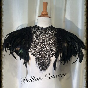 May include: Black lace collar with black feather shoulder pieces. The collar is a delicate lace design and the feathers are soft and fluffy. The collar is on a white mannequin. The text "Dellton Couture" is at the bottom of the image.