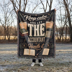 Puede incluir: Manta negra con el texto "Keep calm and let the accountant handle it". La manta presenta ilustraciones de libros de contabilidad, una calculadora y documentos financieros. La manta tiene un borde con flecos.