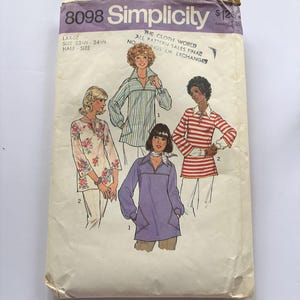 May include: A vintage Simplicity 8098 sewing pattern envelope for a large size 22 1/2 - 24 1/2 half-size top. The cover features illustrations of four different shirt styles, including floral, striped, and solid color designs with long sleeves.