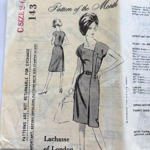 May include: A vintage sewing pattern envelope for a Lachasse of London dress, labeled Pattern of the Month 143, size C. The front features black line illustrations of a dress with a belt and short sleeves, along with printed text and instructions.