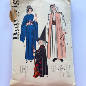 May include: A vintage Butterick printed pattern envelope 6343 for costumes, featuring illustrations of a blue kimono, a long robe with a headpiece, and a black witch robe with red stars and moons. The paper envelope shows chest size 26 and 45c.