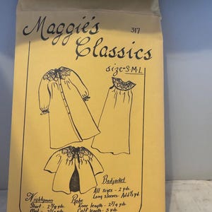 May include: A tan paper sewing pattern envelope titled Maggie's Classics 317. The front features black line drawings of a nightgown, a robe, and a bedjacket with smocked necklines. Text includes size S-M-L and fabric yardage requirements in yards.