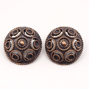 May include: A pair of round, copper-toned earrings with a delicate, intricate design of overlapping circles.