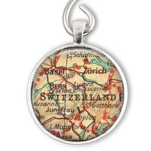 May include: A silver ornament featuring a vintage map of Switzerland with the text "SWITZERLAND" and city names like "Zurich", "Bern", and "Lucerne".