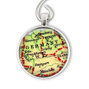 May include: A silver ornament featuring a vintage map of Germany with red lines and the text "GERMANY" in red. The ornament is round and has a silver hook for hanging.